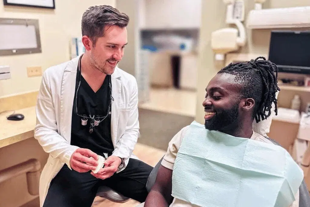 dentist-brendan-vastlik-holding-denture-patient